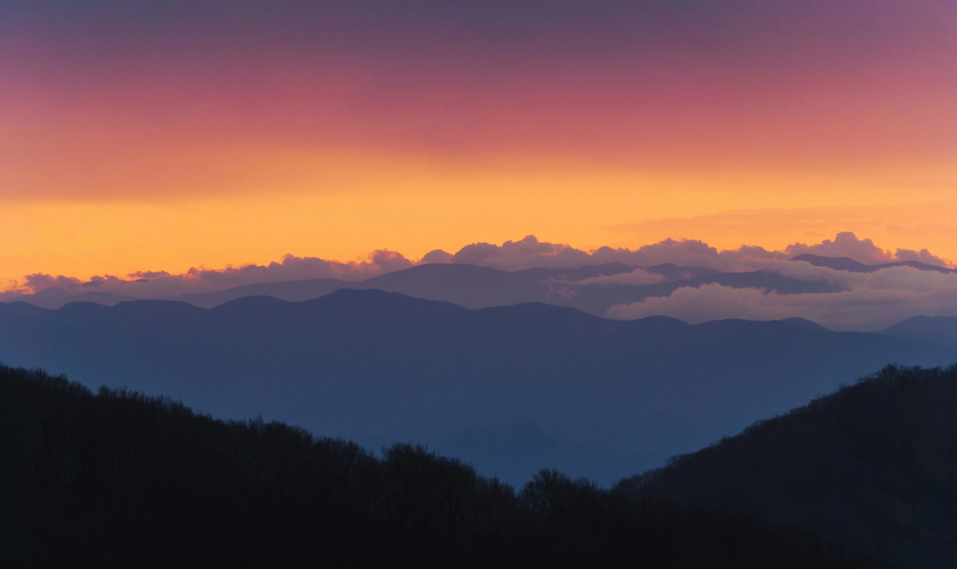 Layered Blue Ridge mountain ridgelines receding into haze under a glowing sunset sky